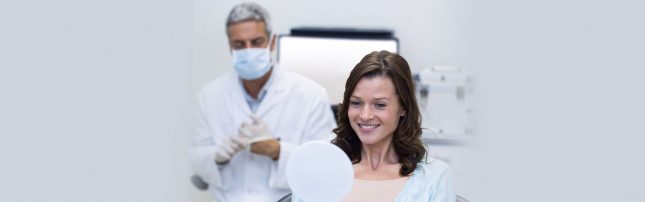 Checking her teeth and gum into mirror after treatment
