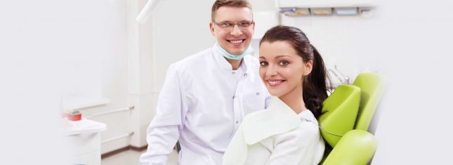 Dentist and patient smiling in treatment room