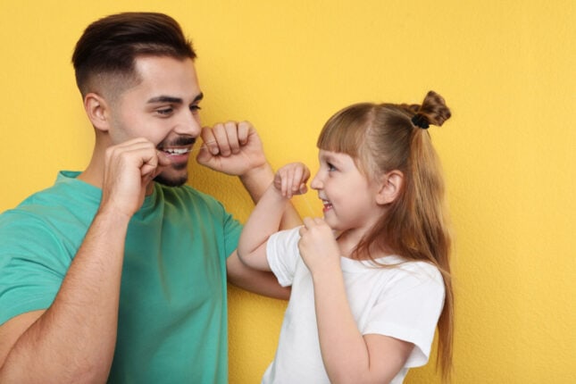 father teaching daughter to floss preventive dental care for families