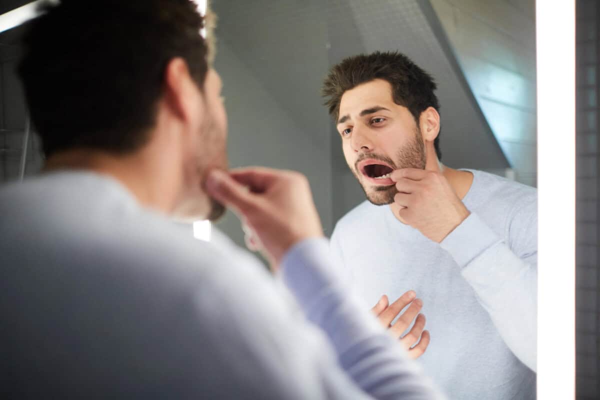 man checking dental bridges for missing teeth in the mirror