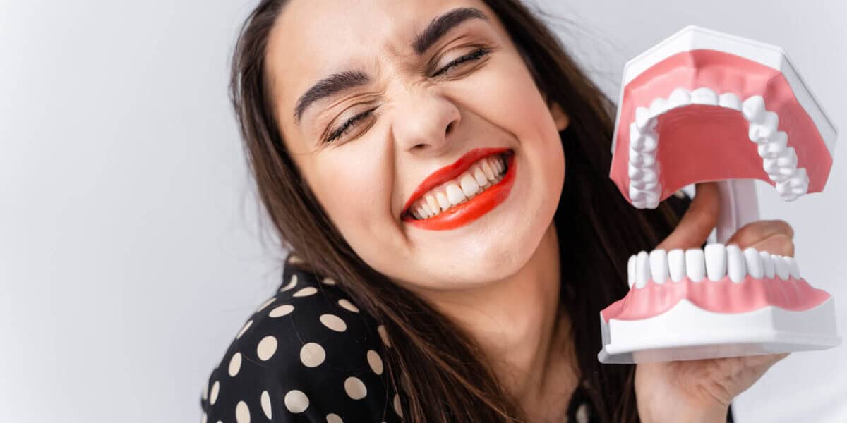 woman after getting Dental Bridges Cartersville GA holding a tooth model